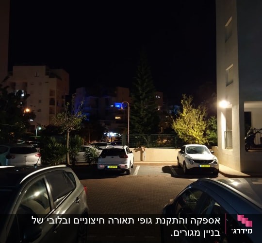 חניון בלילה עם מכוניות חונות ותאורת רחוב